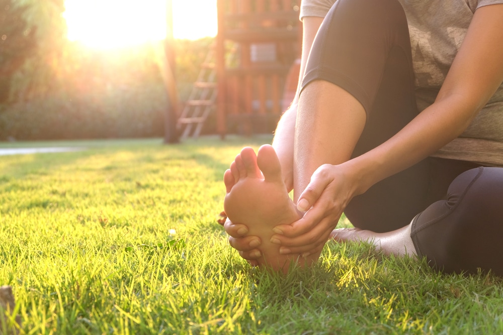 Foot,Pain,.woman,Sitting,On,Grass,Her,Hand,Caught,At
