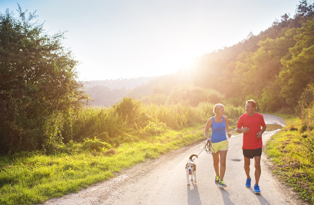 Active,Seniors,Running,With,Their,Dog,Outside,In,Green,Nature